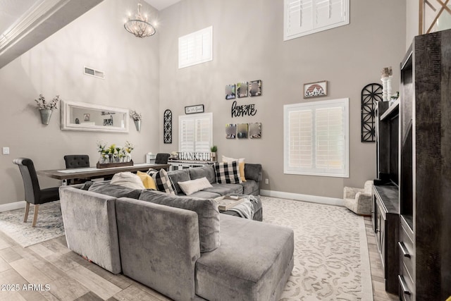 597 S 221st Dr, Buckeye, AZ 85326 - living room with baseboards, light wood finished floors, a towering ceiling, and a chandelier