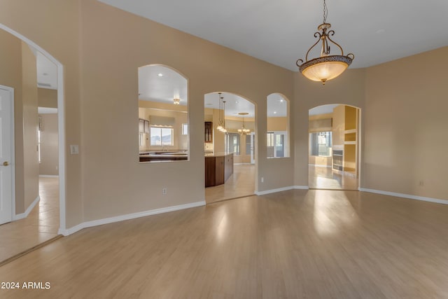 empty room featuring a chandelier and light hardwood / wood-style floors