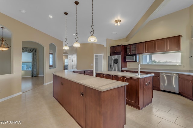 kitchen with a center island with sink, a wealth of natural light, decorative light fixtures, light tile patterned flooring, and stainless steel appliances