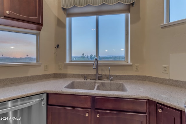 kitchen with light stone countertops, dishwasher, and sink