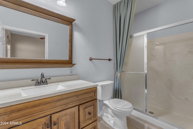 bathroom with tile patterned flooring, vanity, toilet, and a shower with door