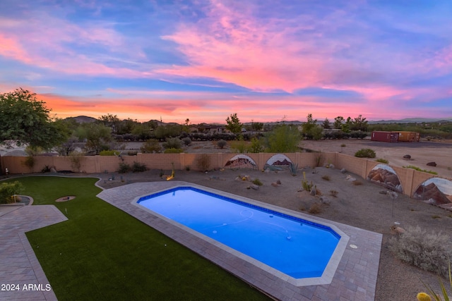 pool at dusk with a lawn and a patio