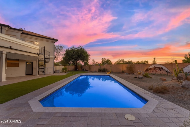 pool at dusk with a yard and a patio area