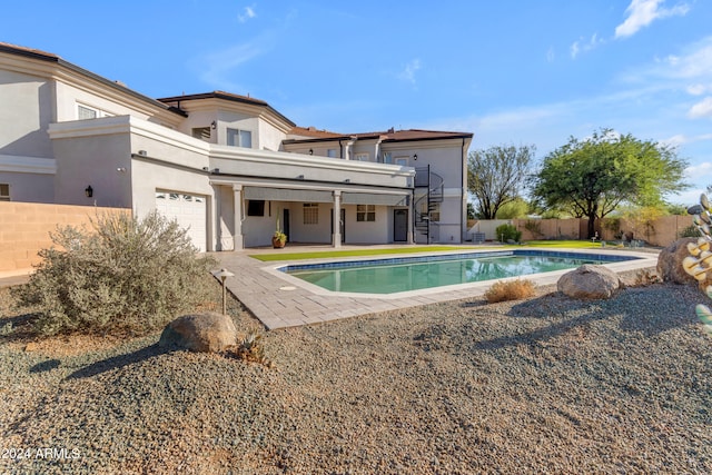 back of property featuring a garage, a fenced in pool, and a patio