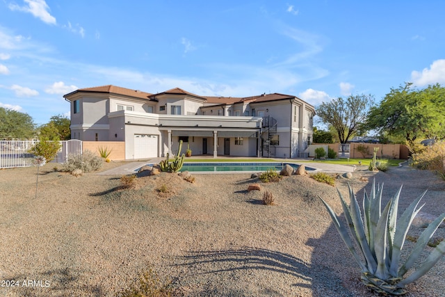 rear view of property with a fenced in pool and a garage