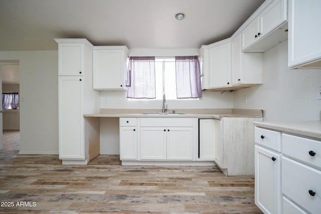 kitchen featuring white cabinets, a sink, light wood-style floors, and light countertops