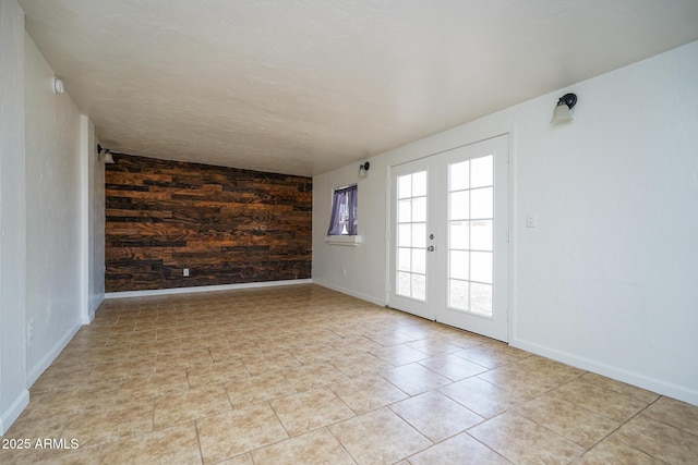 spare room with baseboards, an accent wall, and light tile patterned floors