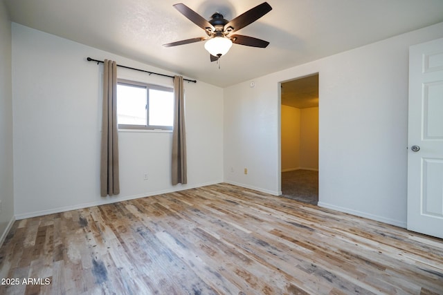 empty room with baseboards, wood finished floors, and ceiling fan