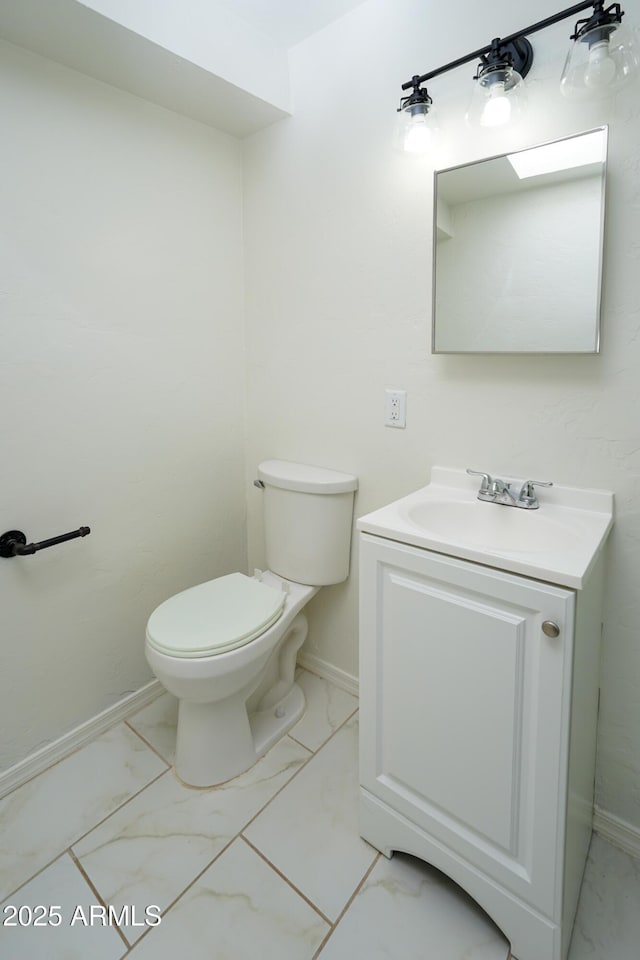 bathroom featuring marble finish floor, vanity, toilet, and baseboards
