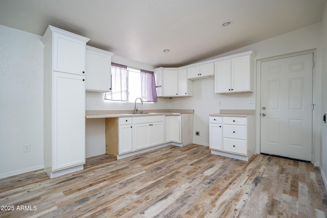 kitchen with white cabinets, a sink, and light wood finished floors