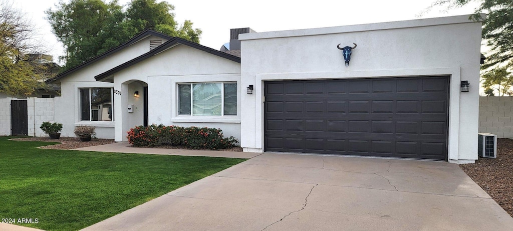 view of front of house featuring cooling unit, a garage, and a front lawn