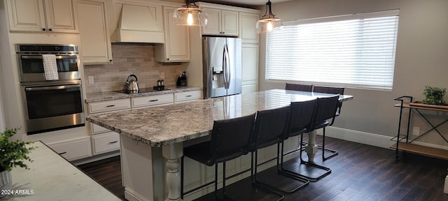 kitchen featuring light stone countertops, custom range hood, stainless steel appliances, and pendant lighting