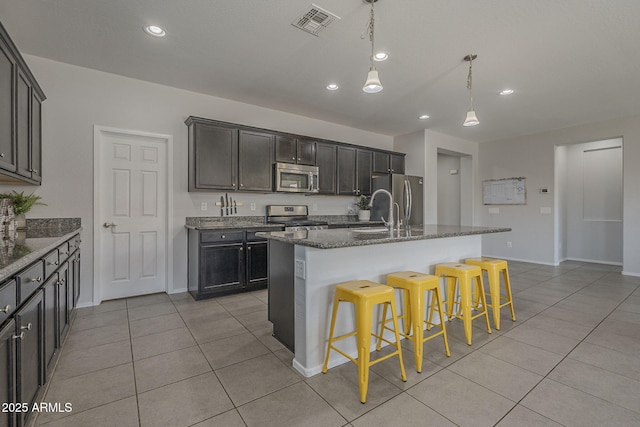 22463 E Desert Spoon Dr, Queen Creek, AZ 85142 - kitchen with stainless steel appliances, light tile patterned flooring, a breakfast bar area, dark stone counters, and recessed lighting