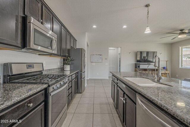 22463 E Desert Spoon Dr, Queen Creek, AZ 85142 - kitchen with stainless steel appliances, a sink, dark stone countertops, ceiling fan, and light tile patterned floors