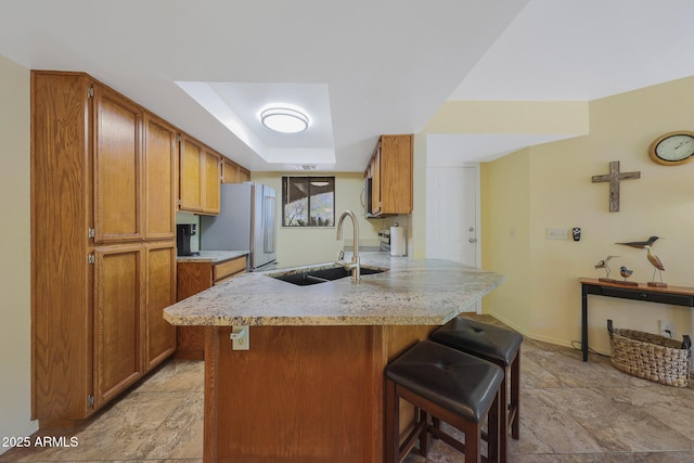 16108 E Emerald Dr Unit 106, Fountain Hills, AZ 85268 - kitchen with freestanding refrigerator, a kitchen breakfast bar, brown cabinets, and light stone finish flooring