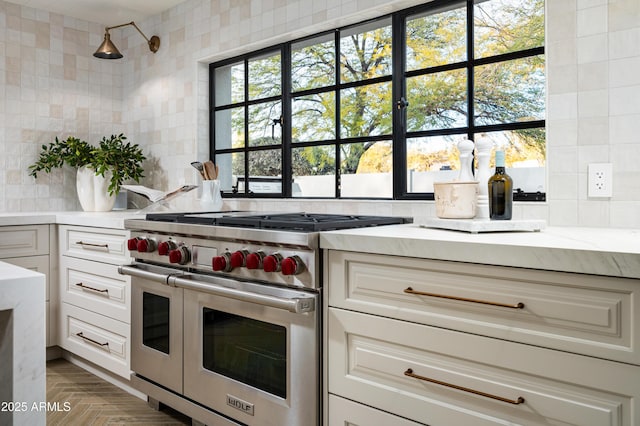 kitchen featuring tasteful backsplash, white cabinetry, and range with two ovens