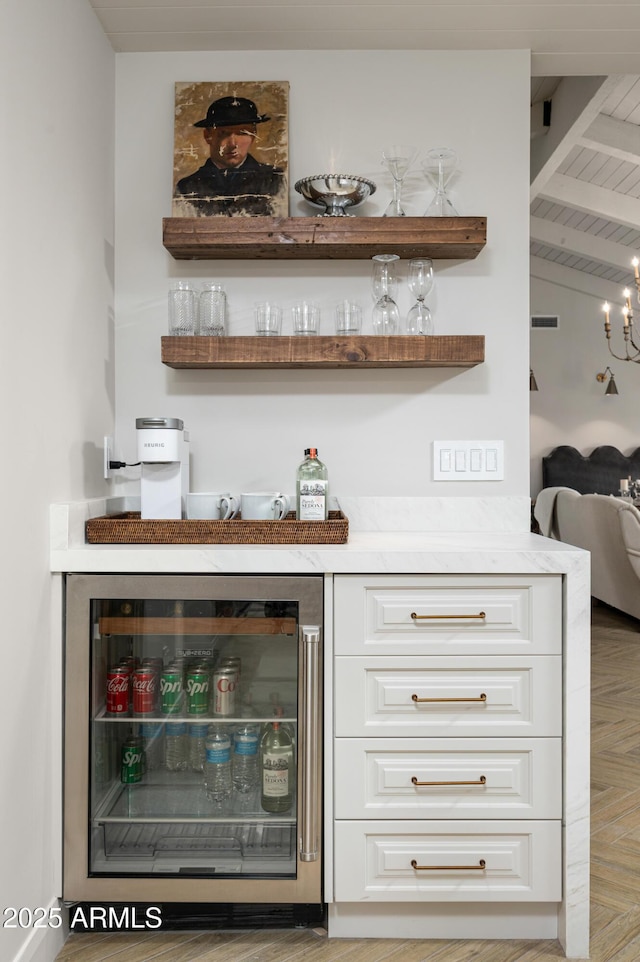 bar featuring a notable chandelier, white cabinetry, vaulted ceiling with beams, and wine cooler