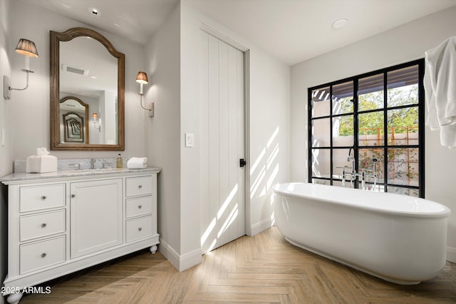 bathroom with vanity, a tub to relax in, and parquet flooring