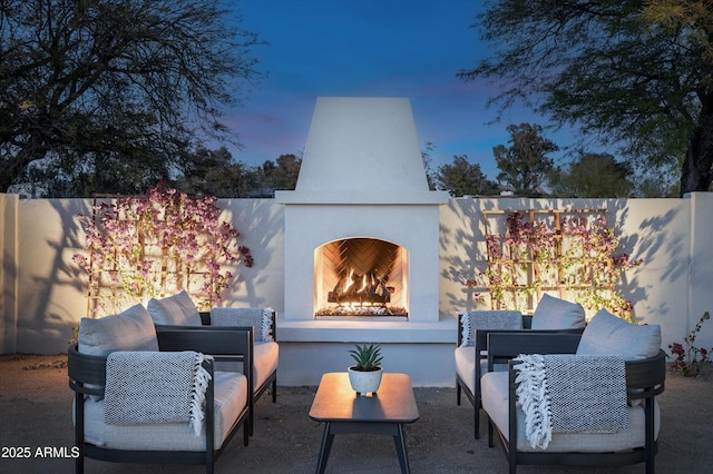 patio terrace at dusk featuring an outdoor fireplace