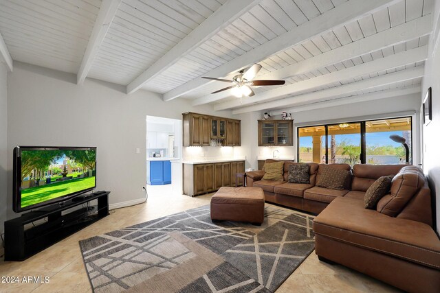 living room featuring beamed ceiling, light tile patterned flooring, and ceiling fan