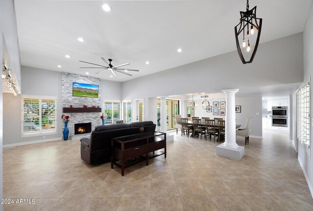 living room featuring a wealth of natural light, decorative columns, a fireplace, and ceiling fan