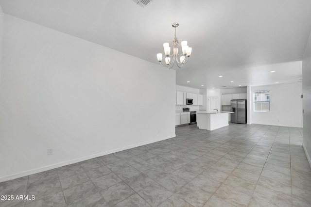 unfurnished living room featuring sink and a notable chandelier