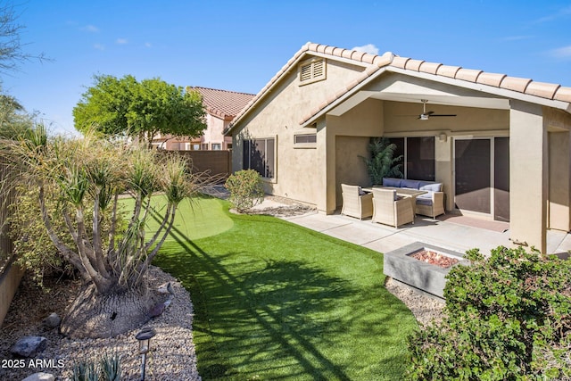 rear view of property featuring ceiling fan, a yard, a patio, and an outdoor living space with a fire pit