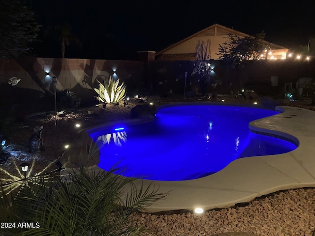 view of pool at twilight