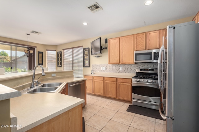 kitchen featuring sink, hanging light fixtures, light tile patterned floors, appliances with stainless steel finishes, and decorative backsplash