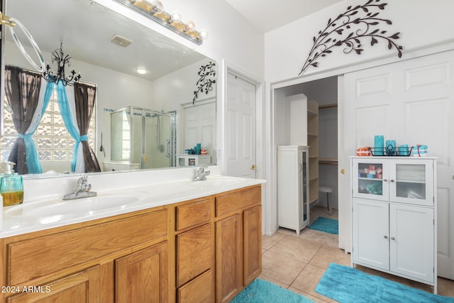 bathroom with a shower with door, vanity, and tile patterned flooring