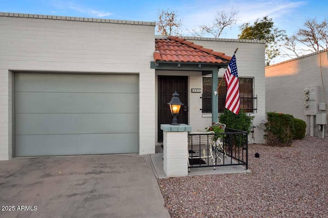 view of front of house with driveway, a tile roof, and a garage