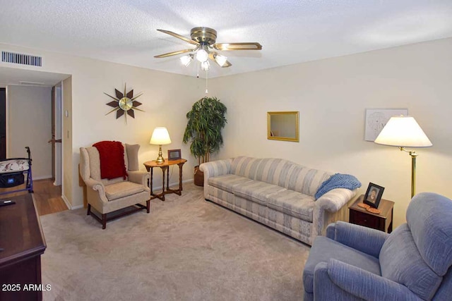 living room featuring a textured ceiling, ceiling fan, carpet floors, visible vents, and baseboards