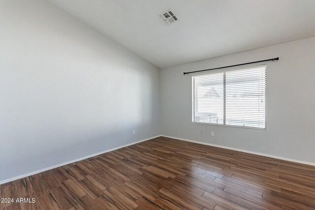 spare room with vaulted ceiling and dark hardwood / wood-style flooring