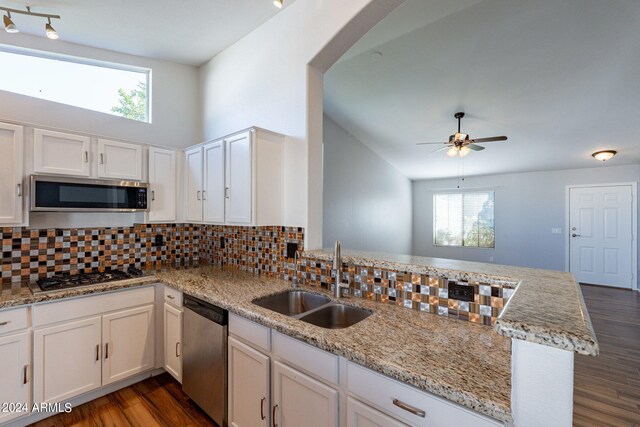 kitchen with stainless steel appliances, kitchen peninsula, sink, dark wood-type flooring, and white cabinets