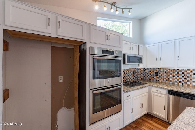 kitchen featuring appliances with stainless steel finishes, white cabinetry, tasteful backsplash, and light hardwood / wood-style floors