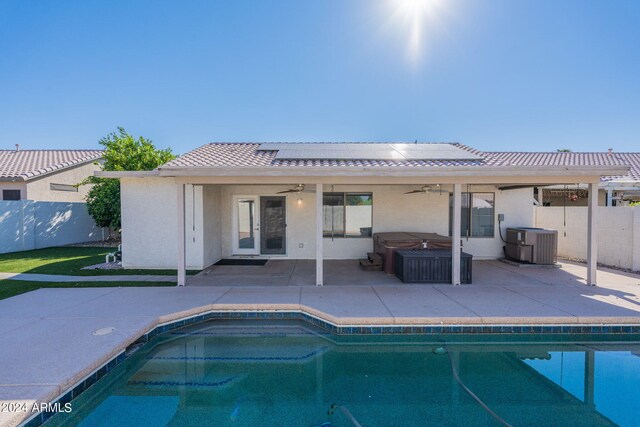 rear view of property featuring central AC unit, ceiling fan, a patio area, and a swimming pool with hot tub