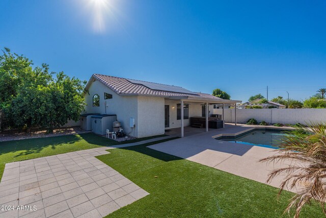 rear view of property with a fenced in pool, a yard, and a patio area