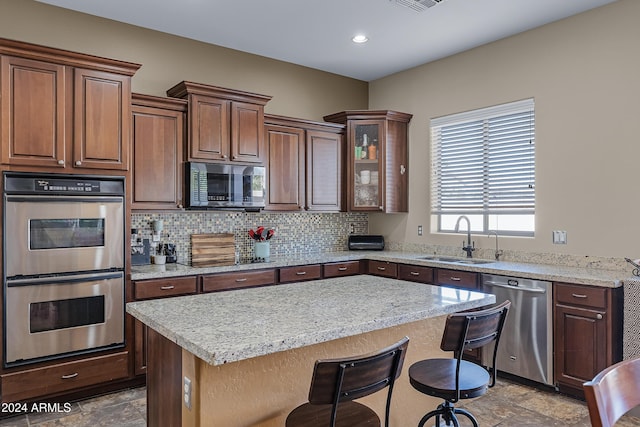 kitchen with decorative backsplash, a kitchen breakfast bar, stainless steel appliances, sink, and a center island