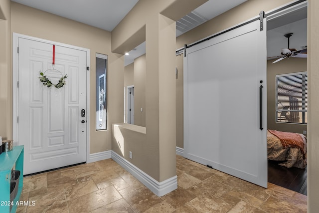 entrance foyer with a barn door and ceiling fan