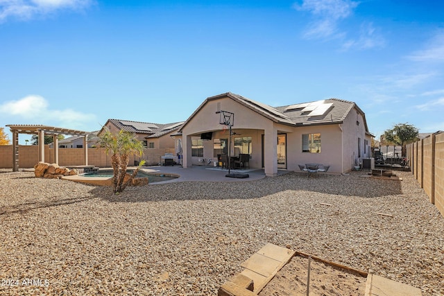 rear view of property with solar panels, ceiling fan, and a patio area