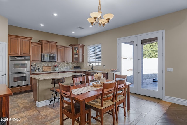 dining space with a chandelier, sink, and french doors