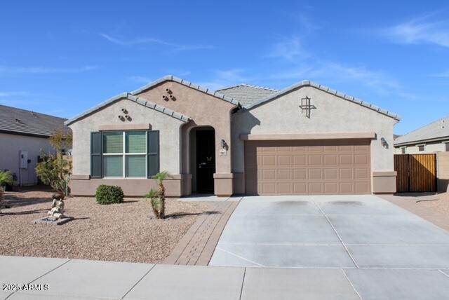 view of front of house with an attached garage, fence, a tile roof, concrete driveway, and stucco siding