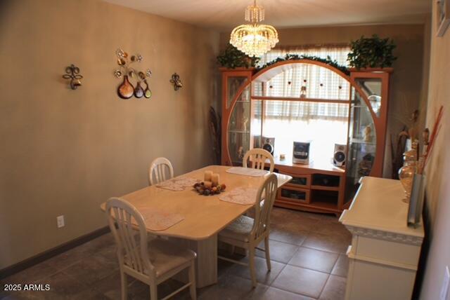 tiled dining space with a chandelier and baseboards