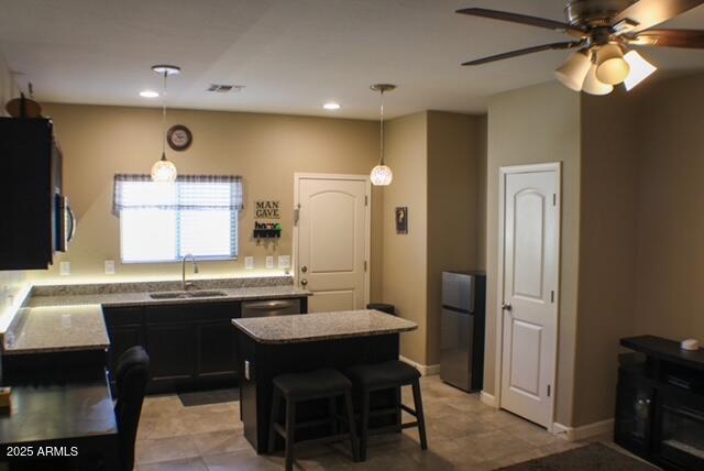 kitchen featuring appliances with stainless steel finishes, pendant lighting, a sink, and a kitchen island