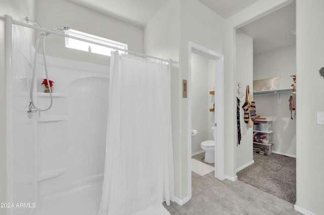 bathroom with tile patterned floors, curtained shower, and toilet