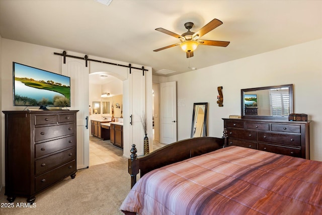 8733 E Jacaranda St, Mesa, AZ 85207 - bedroom featuring arched walkways, a barn door, a ceiling fan, connected bathroom, and light colored carpet