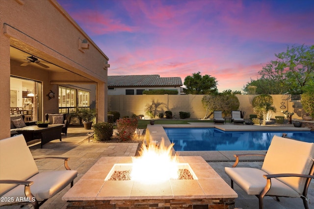 8733 E Jacaranda St, Mesa, AZ 85207 - pool at dusk with a fenced in pool, a patio, a ceiling fan, a fenced backyard, and an outdoor fire pit