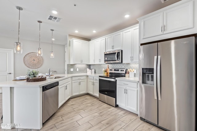 kitchen with visible vents, stainless steel appliances, light countertops, and decorative light fixtures