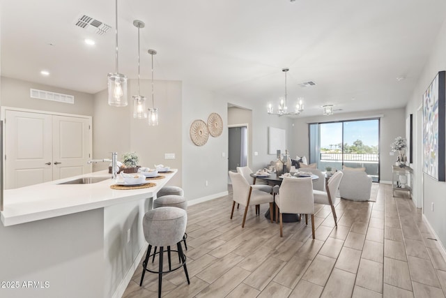 dining space with wood finish floors, visible vents, and a notable chandelier