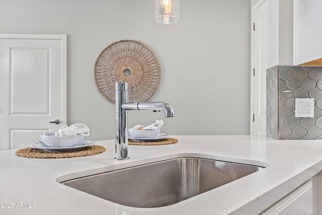 room details with light countertops, a sink, white cabinetry, and pendant lighting